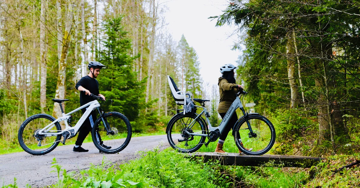 2 Personen auf einem Fahrrad im Wald