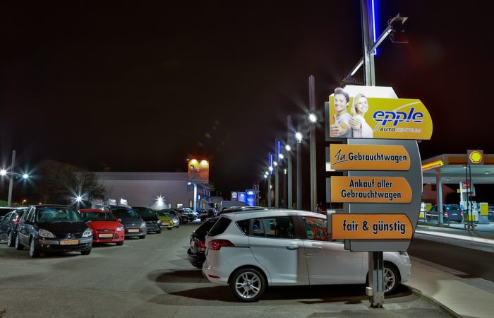 Beleuchteter Gebrauchtwagenplatz bei Nacht mit Wegweiser des Autozentrum Epple in Rutesheim
